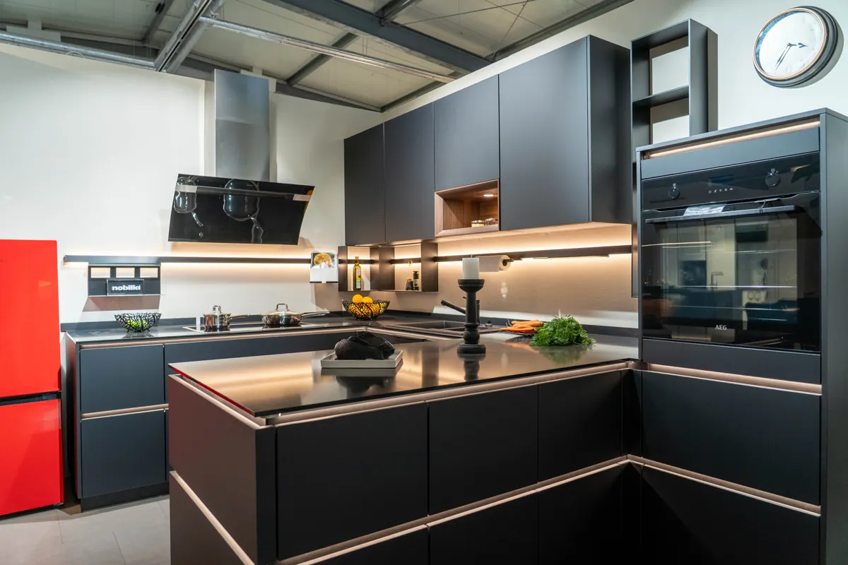 Dunkle Eckküche mit beleuchteter Arbeitsfläche und erhöhtem Backofen