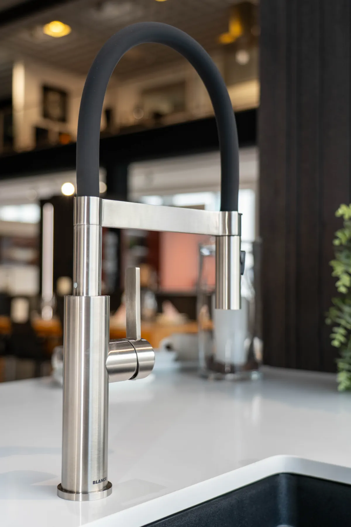 Dunkles Spülbecken mit hoher Metallarmatur vor Holzfronten