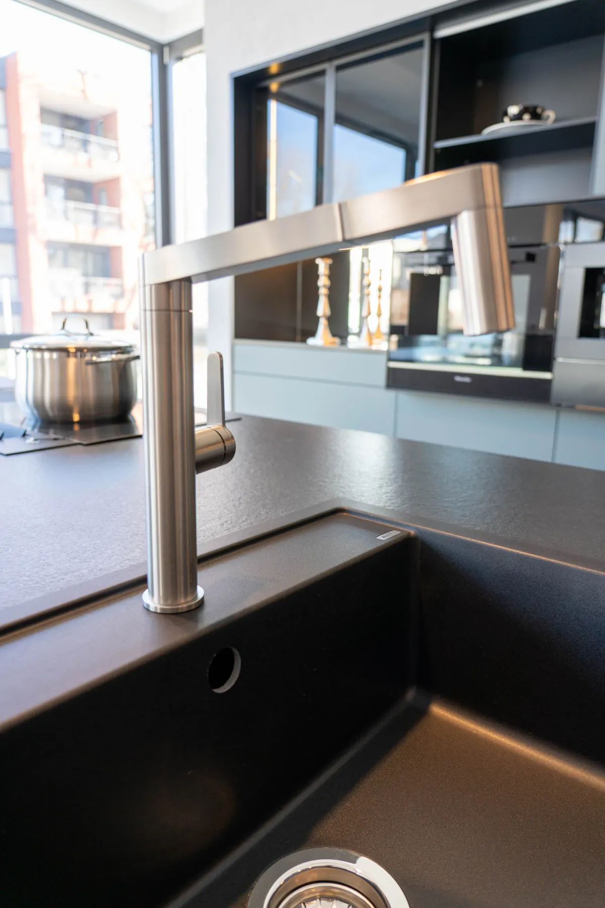 Dunkle Spüle mit Metallarmatur in einer hellen Arbeitsplatte