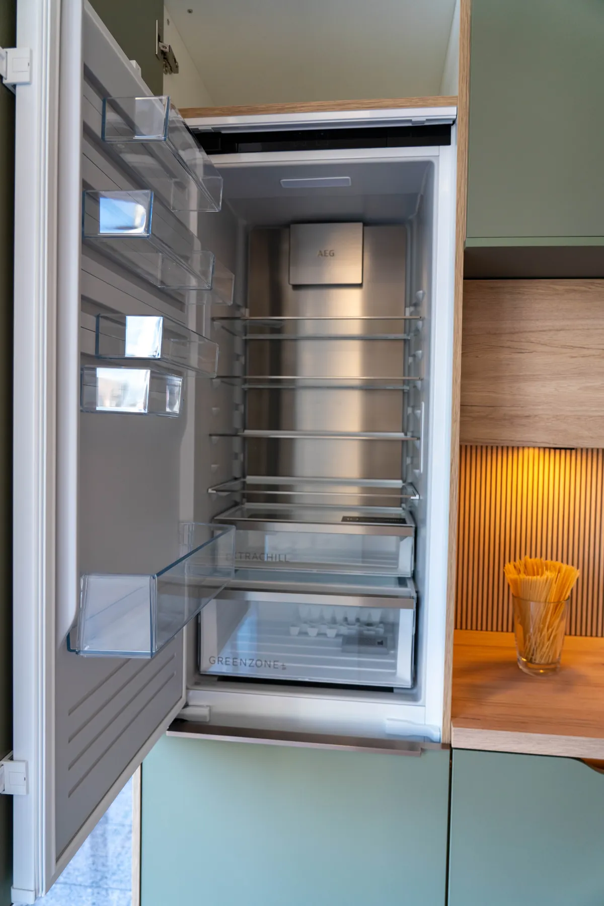 Geöffneter Einbaukühlschrank in grüner Küchenzeile